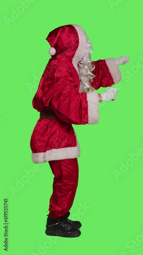 Vertical video Profile of santa choirmaster conducting band, conductor in winter seasonal costume accompany choir over full body greenscreen backdrop. Character pretends to be musical director photo