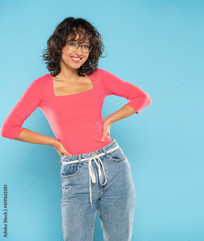 Young smiling exotic brunette woman in pink blouse and rope belt jeans ...