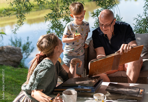 Grandpa with his grandchildren looking at old photo albums on outdoor terrace on a sunny summer day photo