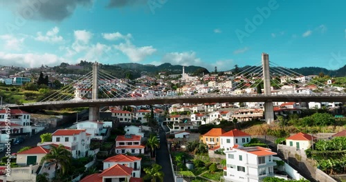 Aerial view of Funchal, Madeira's capital in Portugal. City and mountains in backdrop. Drone flies over houses on Madeira Island. Mountain slope, cable car reveals Funchal.