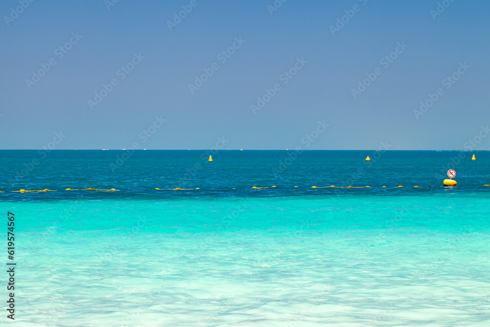 Sea with clear turquoise water and yellow protective buoys in clear day