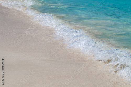 Sea surf with turquoise water close-up on sandy tropical beach, diagonally
