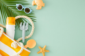 Easy summer skincare routine for children. Top view of sunscreen spray, sandbox toys, eyewear, beach bag, palm leaf, starfish on turquoise background with empty space for promo or text