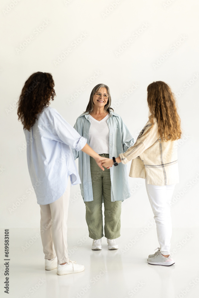 Happy european adult, teen woman and girl in casual holding hands of old grandmother Happy european adult, teen woman and girl in casual holding hands of old grandmother