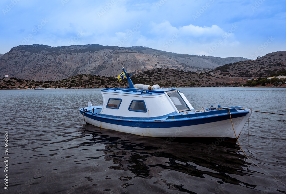 A small traditional greek white and blue fishing boat on water in Symi, Greece. 