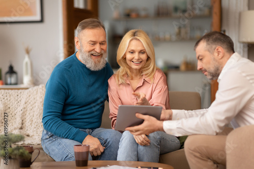 Man Showing Digital Tablet To Happy Senior Couple At Home