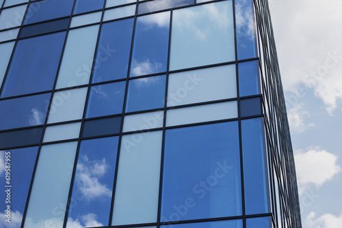 Construction of a glass facade structure. Modern office building  glass and clouds  real-estate investing concept. Place for text  business center with a glass facade. 