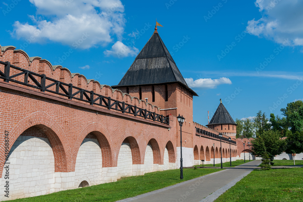 Old Tula Kremlin red brick wall and tower with wooden roof in sunny summer day. Clear blue sky with few clouds. Medieval architecture. Travel in Russia theme.