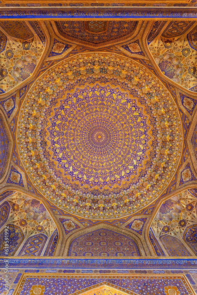 Painted gilded dome of Madrasa Tilya Kori (Registan complex). Arabic text of Koran (sacred book of muslims) used as part of ornament. Gold and blue. Samarkand, Uzbekistan