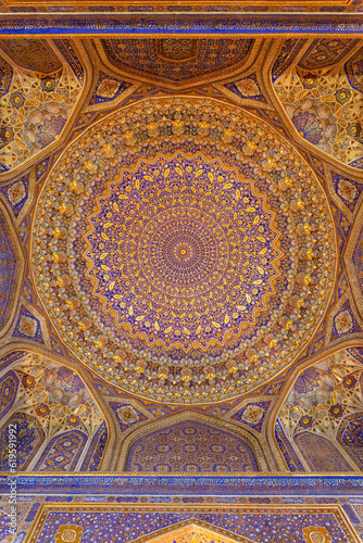 Painted gilded dome of Madrasa Tilya Kori  Registan complex . Arabic text of Koran  sacred book of muslims  used as part of ornament. Gold and blue. Samarkand  Uzbekistan