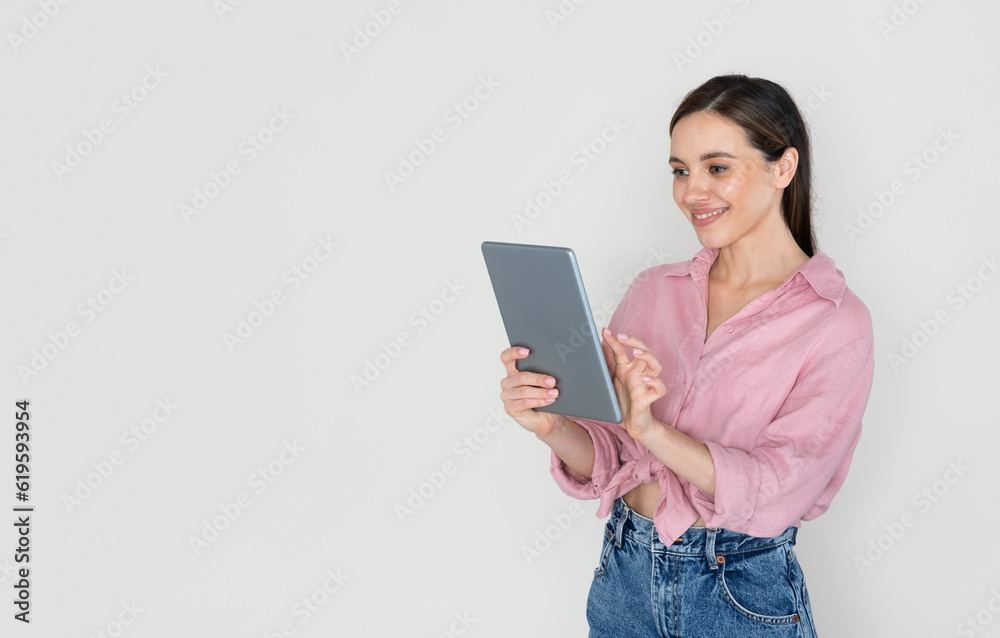 Cheerful young woman using digital tablet and smiling Cheerful young woman using digital tablet and smiling