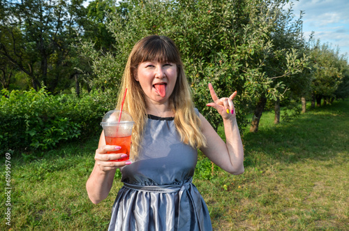 Beauty joyful girl with cold fresh lemonade  shows red tongue. Vacation holiday relax concept.