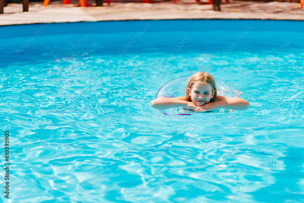 Cute funny teen girl in a swimsuit with an inflatable lifebuoy swims in the pool