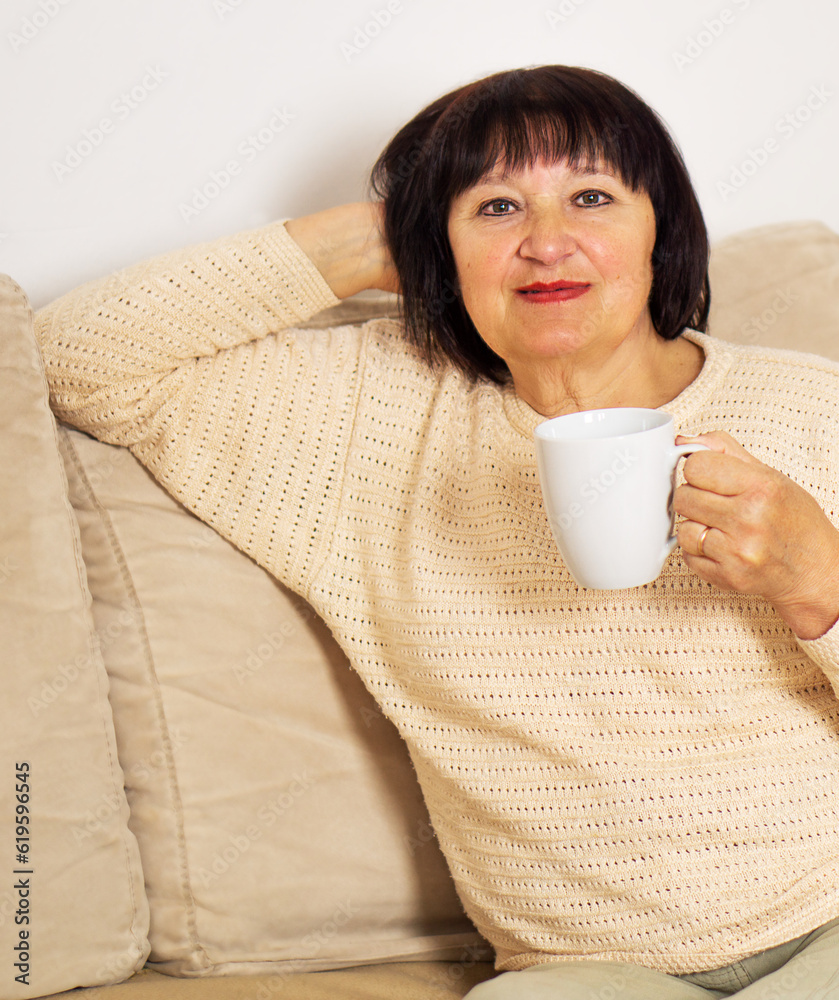 Happy relaxed senior woman in good mood drinking a cup of coffee or hot tea at home. Happy relaxed senior woman in good mood drinking a cup of coffee or hot tea at home.