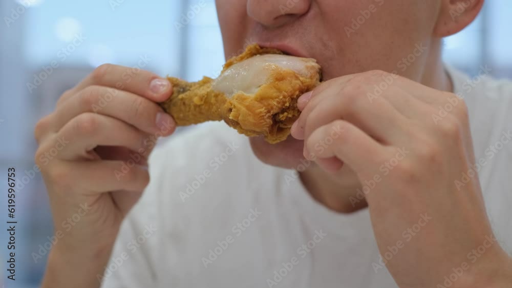A man eats an appetizing fried chicken leg in a fast food restaurant A man eats an appetizing fried chicken leg in a fast food restaurant