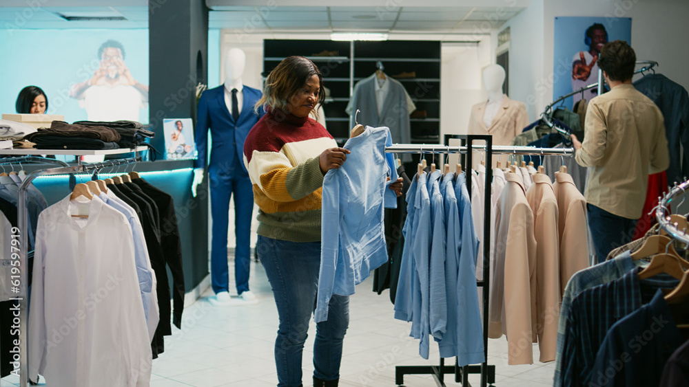 Diverse women talking about fashion brands in retail shop, client and store assistant looking at modern new collection. Two people analyzing clothing store merchandise at mall. Diverse women talking about fashion brands in retail shop, client and store assistant looking at modern new collection. Two people analyzing clothing store merchandise at mall.