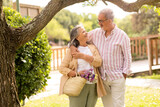 Positive old european husband hugging wife, enjoy walk together in park, holiday in city, outdoor