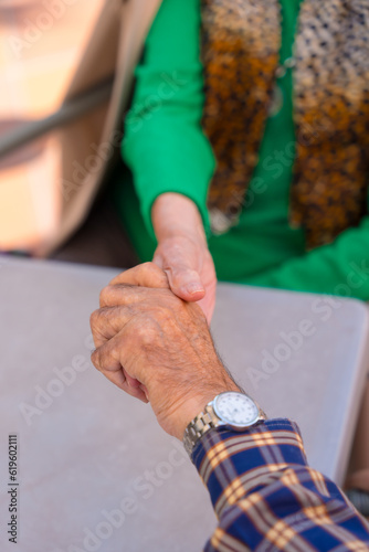 Detail of the hands of two elderly people in the garden of a nursing home or retirement home holding hands in a moment of affection © unai