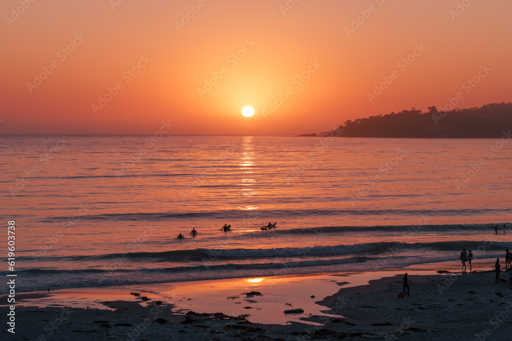 Sunset on the sea with surfers in Carmel, California