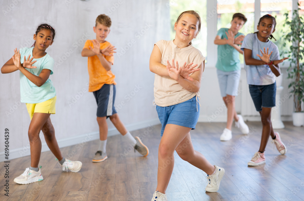 Positive cheerful smiling children studying modern style dance in class indoors