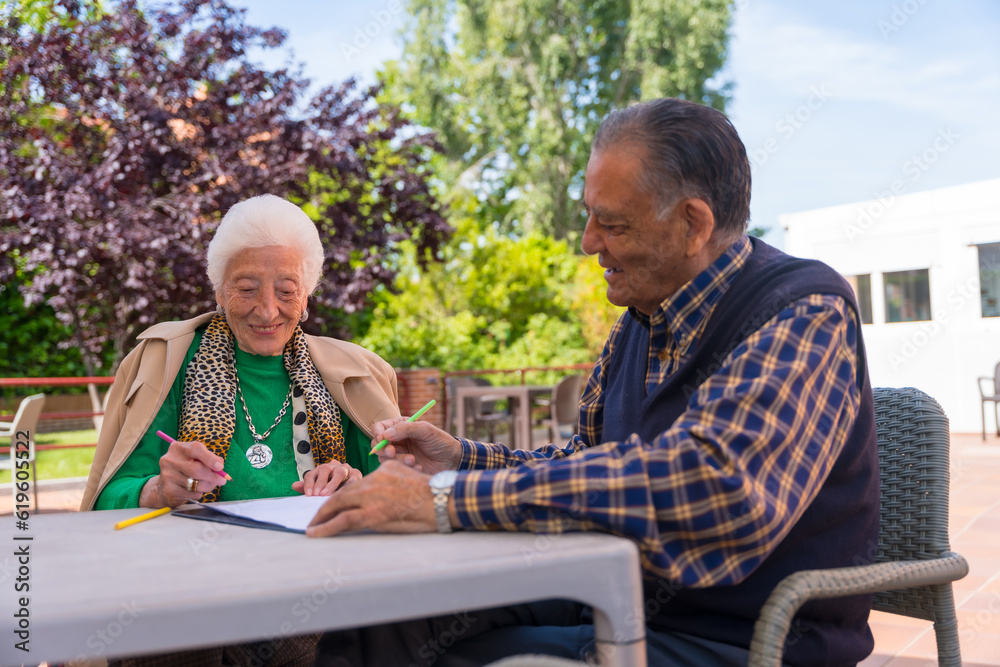 Two elderly people painting in the garden of a nursing home or retirement home, old man and old woman Two elderly people painting in the garden of a nursing home or retirement home, old man and old woman