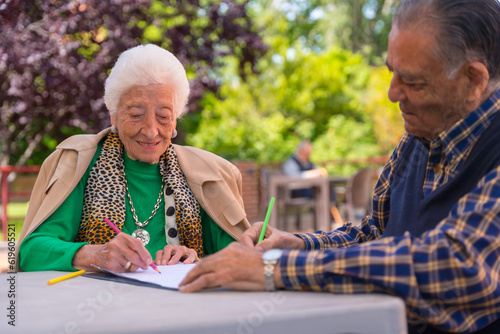 Two elderly people painting in the garden of a nursing home or retirement home
