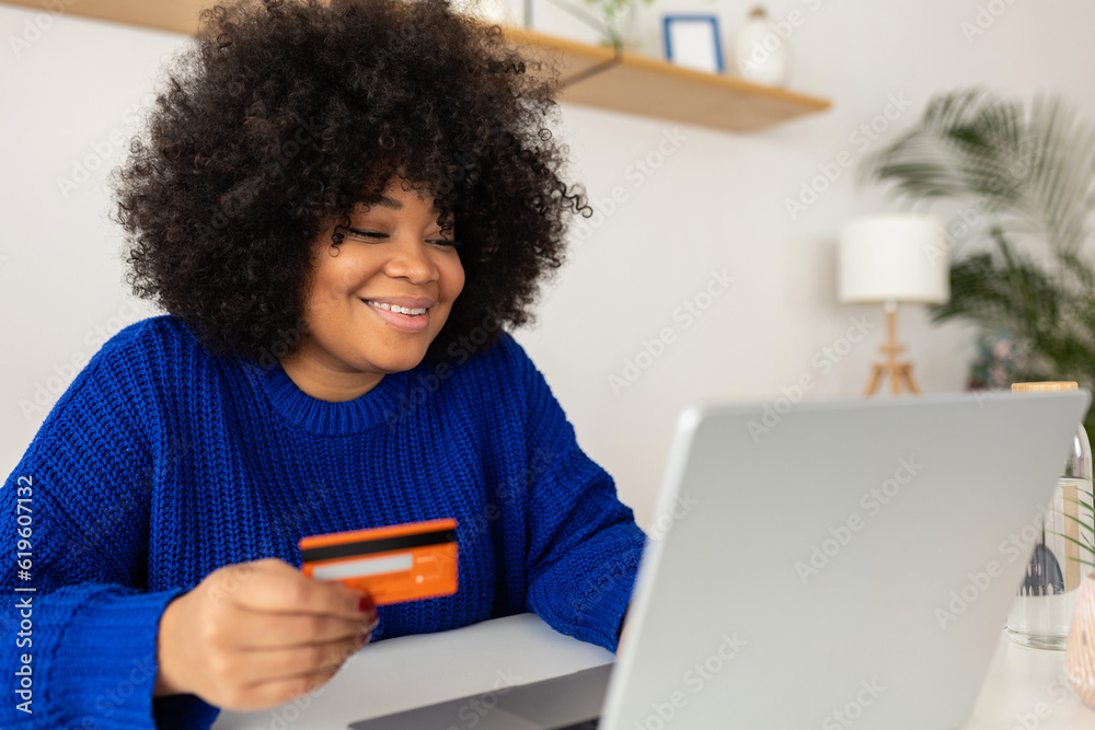 Latina beautiful woman buying online using credit card and laptop computer sitting on table at home. Online shopping and electronic banking concept. Latina beautiful woman buying online using credit card and laptop computer sitting on table at home. Online shopping and electronic banking concept.