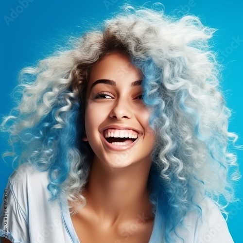 Beautiful young woman with white long curly blue hair. Portrait of a happy beautiful blonde girl, studio shot. Beauty, fashion. Happy women concept. Laughing young woman with healthy white teeth