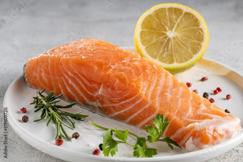 Fresh raw salmon fillet with ingredients for preparation.