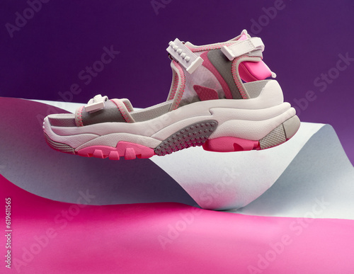 Trendy Female sport grey-white-pink sandal on the multicolor paper background lavitating. photo