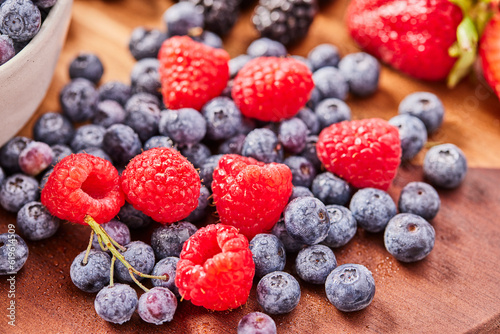 Studio shot of fresh blueberries and raspberries on wooden surface