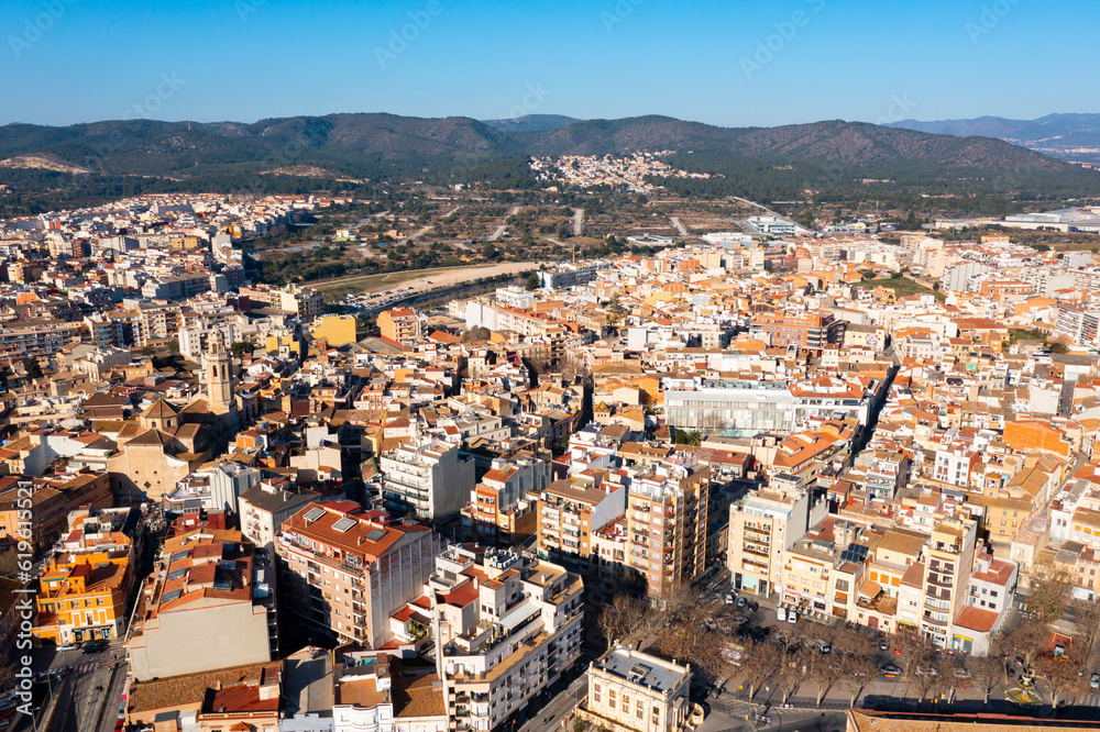 View from drone of El Vendrell cityscape with brownish roofs of residential buildings on sunny winter day, Catalonia, Spain..