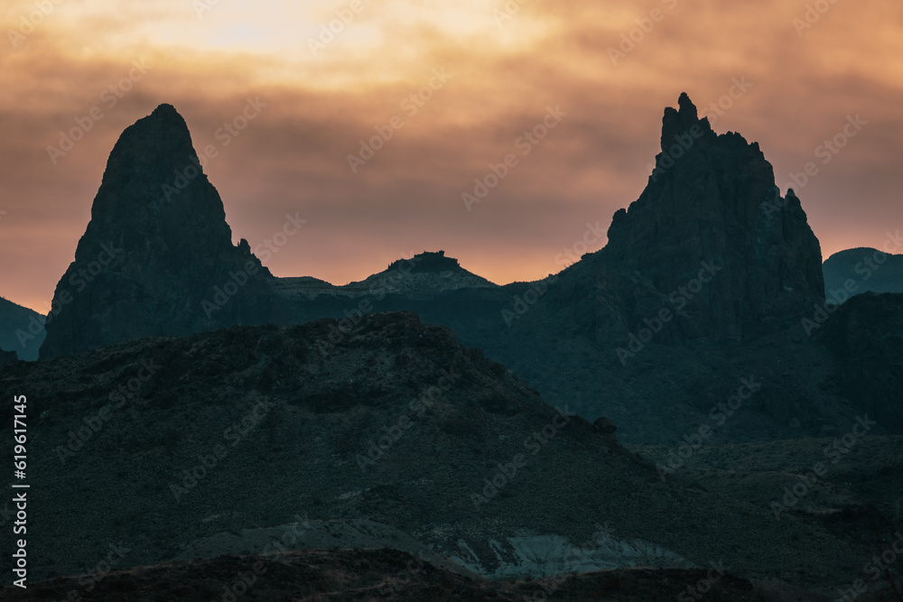 Mule Ears Silhouetted Against Menacing Orange Clouds In Big Bend