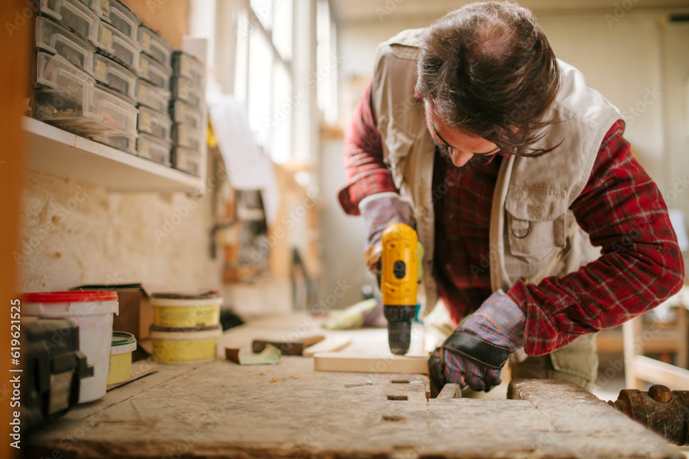 Mature carpenter working in his woodworking workshop