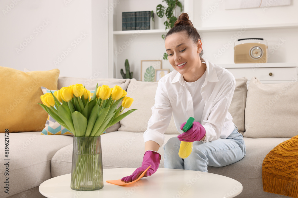 Spring cleaning. Young woman tidying up living room at home Spring cleaning. Young woman tidying up living room at home