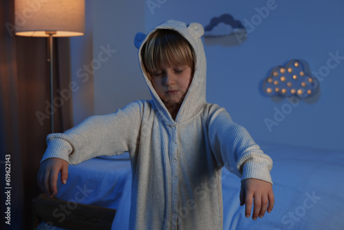 Boy in pajamas sleepwalking indoors at night photo