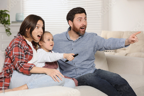 Surprised family watching TV on sofa at home