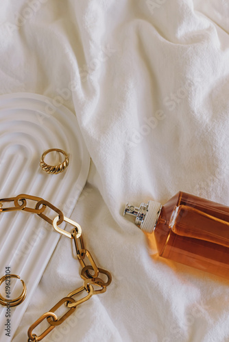 Still life composition with golden jewelry and bottle of perfume