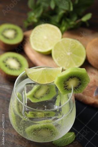 Glass of refreshing drink with kiwi and lime on table photo