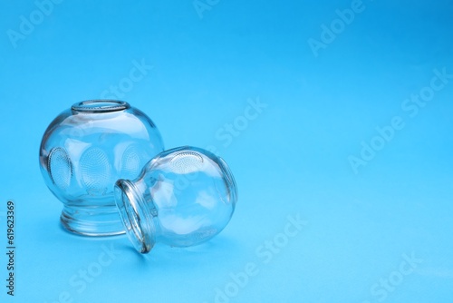 Glass cups on light blue background  space for text. Cupping therapy