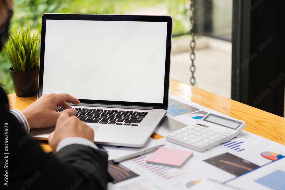 Young financial market analyst working at office with laptop while sitting at wooden table Businessman analyzing documents on his desk close up pictures Young financial market analyst working at office with laptop while sitting at wooden table Businessman analyzing documents on his desk close up pictures
