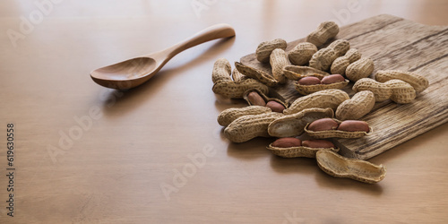 Peanuts on the cutting board and wooden spoon on a wooden table photo