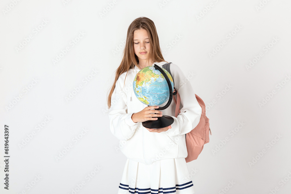 Study, education, school, university, college, graduate concept. Beautiful smiling and happy school girl with backpack and school globe in hands is posing on white background Study, education, school, university, college, graduate concept. Beautiful smiling and happy school girl with backpack and school globe in hands is posing on white background