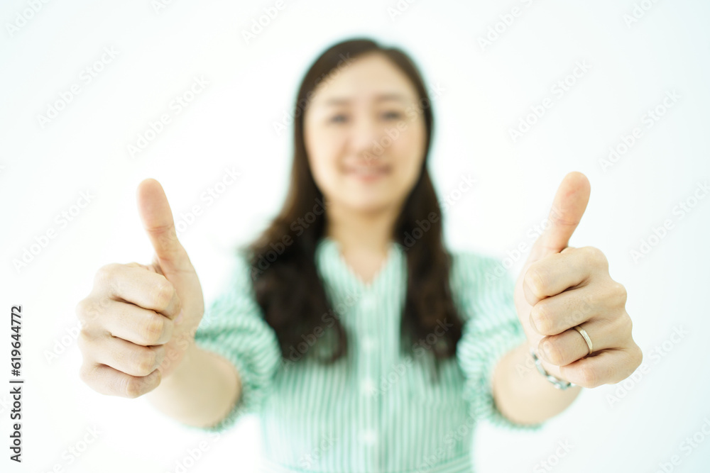 Happy cheerful Asian young adult woman showing thumb up and smiles to camera, Asian woman in action portrait on white background. Happy cheerful Asian young adult woman showing thumb up and smiles to camera, Asian woman in action portrait on white background.