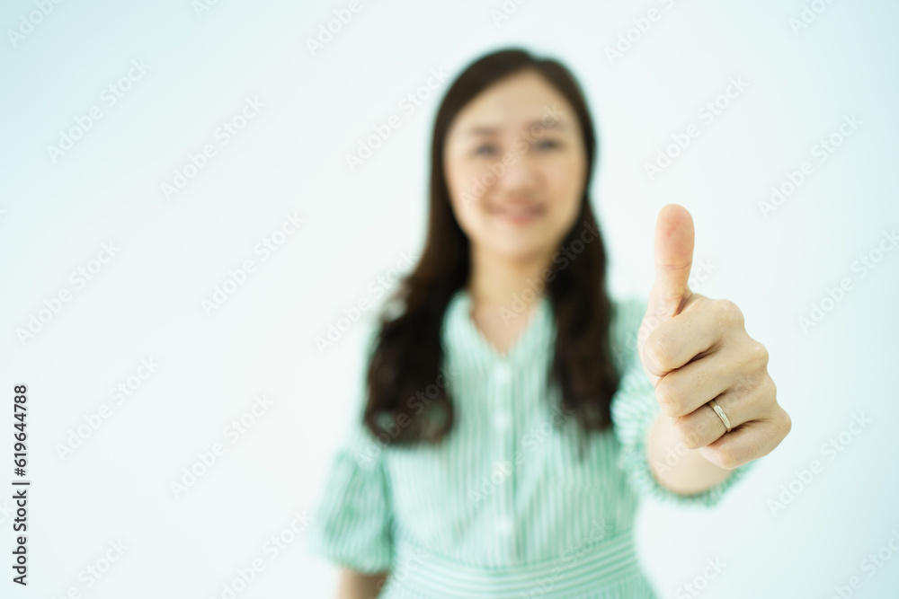 Happy cheerful Asian young adult woman showing thumb up and smiles to camera, Asian woman in action portrait on white background. Happy cheerful Asian young adult woman showing thumb up and smiles to camera, Asian woman in action portrait on white background.