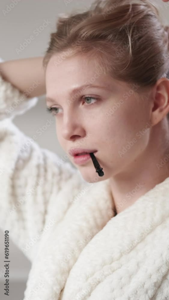 Vertical video. Beauty routine. Hair accessory. Morning spa. Relaxed confident blonde woman with clean pretty face skin tying bun with pin. Vertical video. Beauty routine. Hair accessory. Morning spa. Relaxed confident blonde woman with clean pretty face skin tying bun with pin.