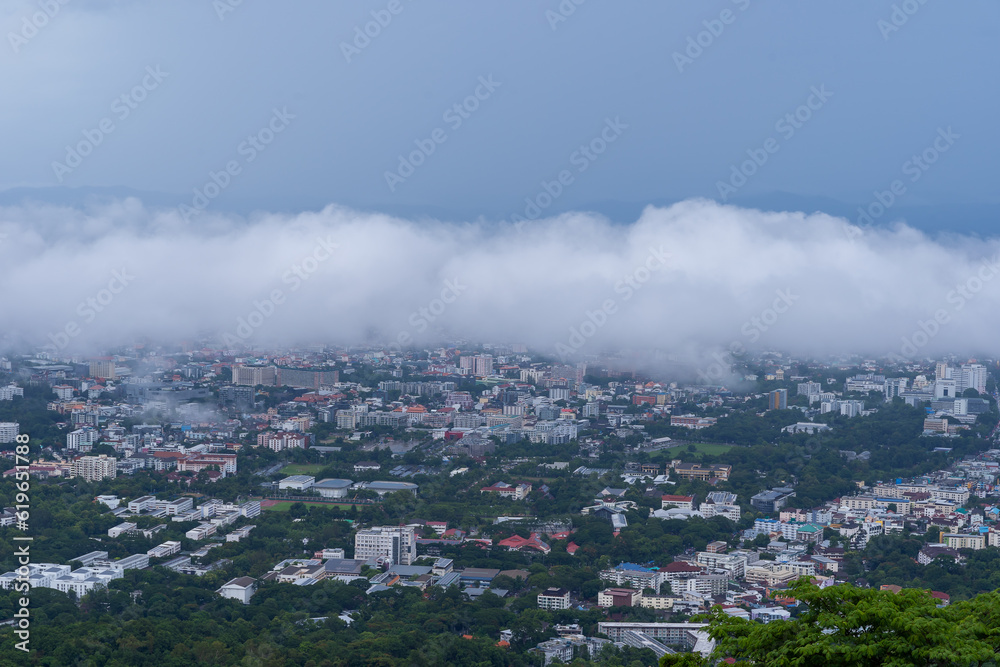 Fog covers the city and houses. A beautiful aerial view of Chiang Mai Thailand with sea fog covering the building, airport and parts of the city. Revealing part of the business building and road