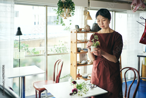 開店前のカフェで花をいける日本人女性