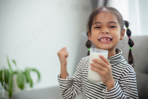Konstfotografi Asian little cute kid holding a cup of milk in the house