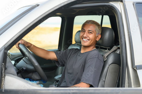 Smiling young Mexican man driving car
